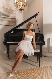 Ivory white beaded tulle bridal mini dress with sheer corset bodice and flared mini skirt worn with white pumps